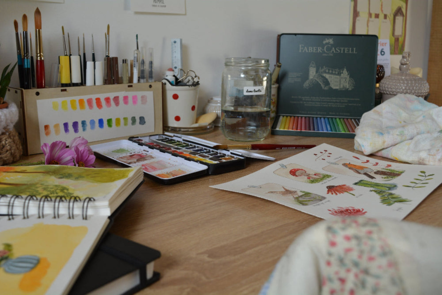 Mon bureau avec mes aquarelles, mes crayons et quelques illustrations.